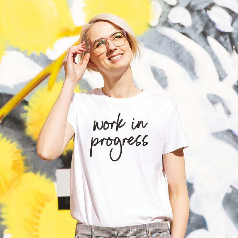 Woman with blonde hair wearing a slogan tee that says Work in Progress